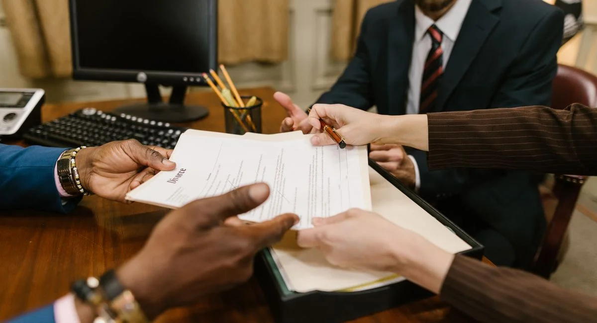 Professional meeting with individuals signing legal documents in an office setting.