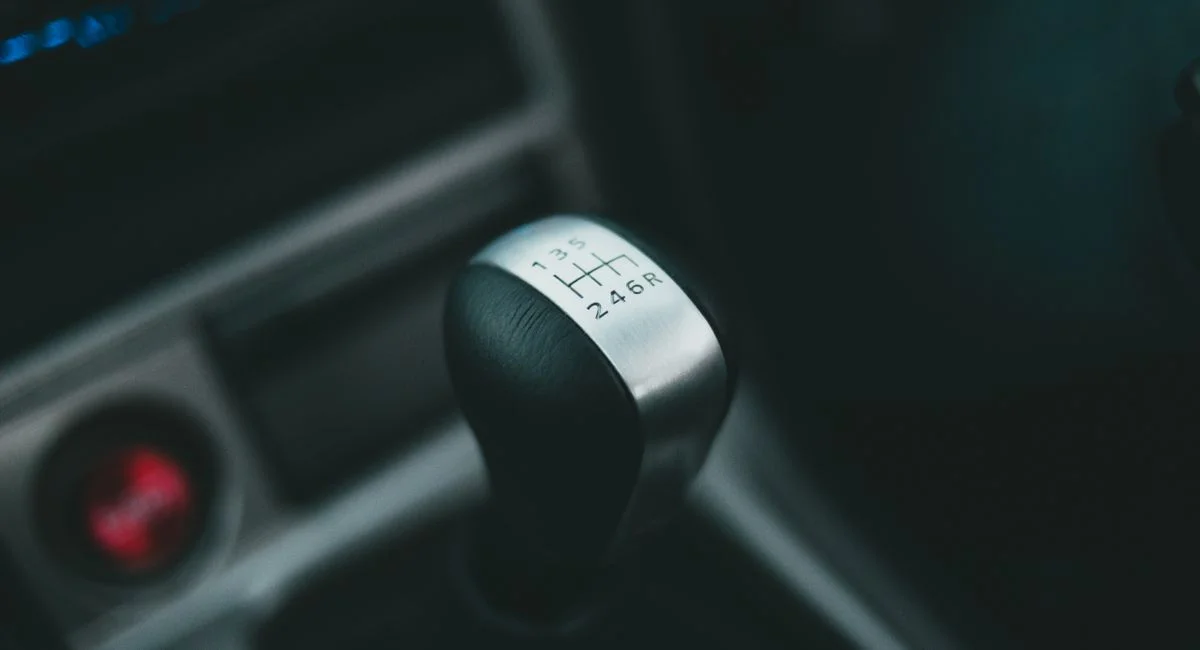 Detailed close-up of a manual gear lever inside a car with blurred background.