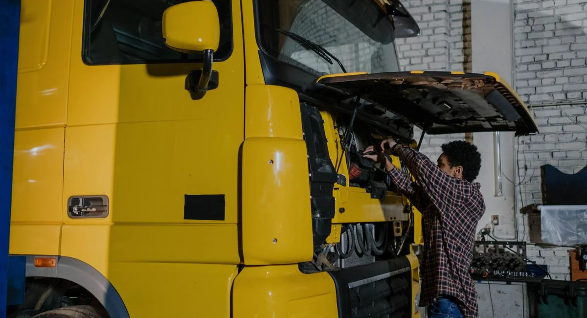 A mechanic working on a truck engine in an indoor mechanical workshop.