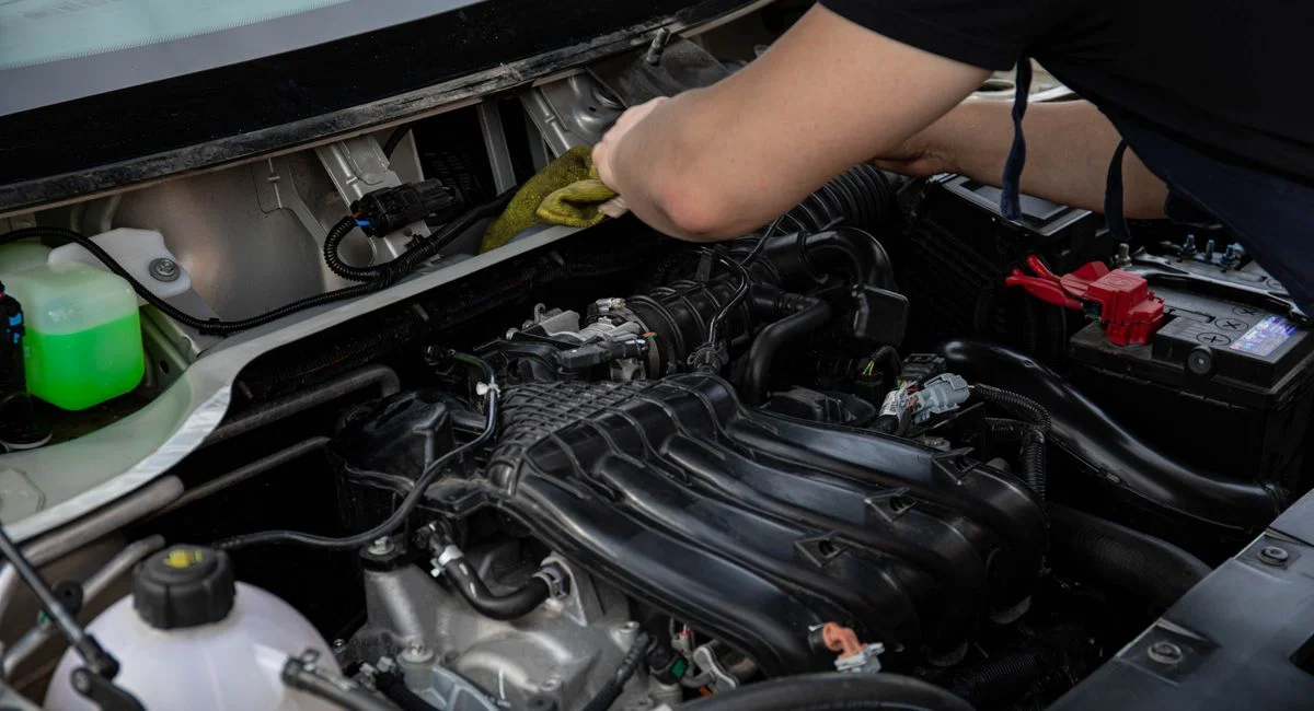 Close-up of a mechanic working on a car engine in a workshop setting.
