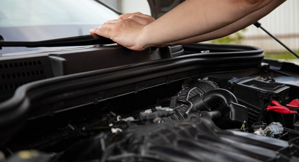 Close-up of hands working on car engine. Detailed view of automotive repair.