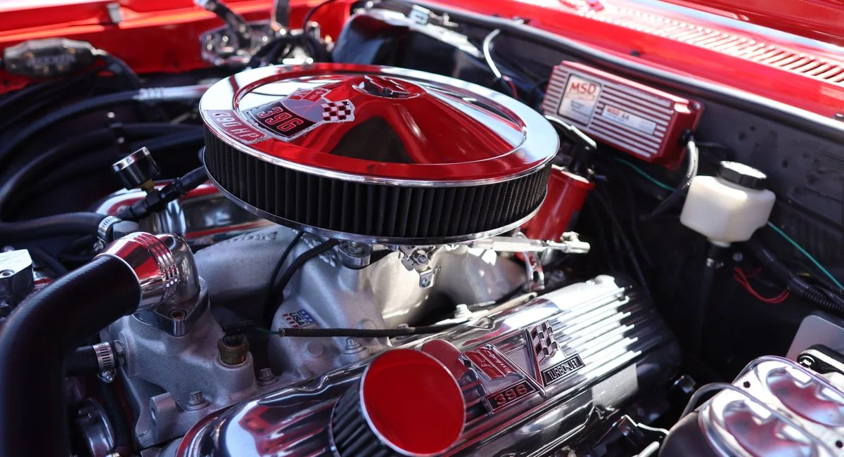 Detailed view of a powerful classic car engine under the hood showcasing intricate parts.