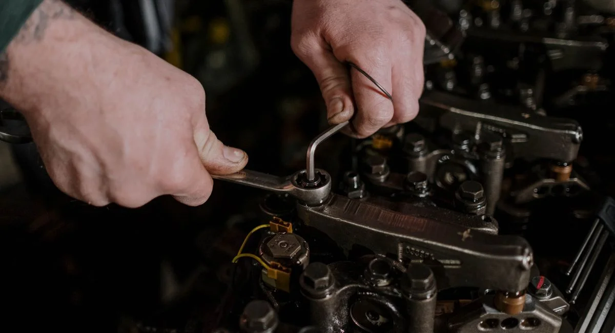 Close-up of a mechanic using a wrench and Allen key to fix an engine.