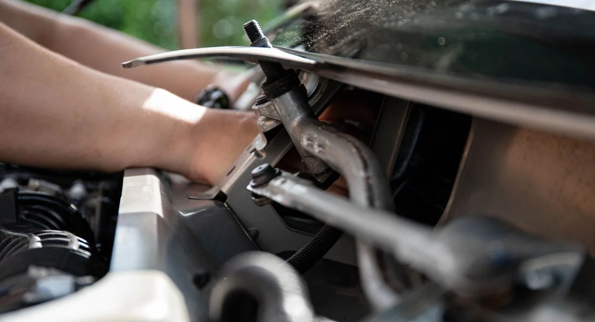 Close-up shot of a mechanic repairing a car engine with focus on tools and hands.