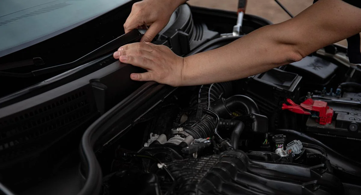 Close-up of mechanic hands fixing a car windshield wiper, showcasing engine components.