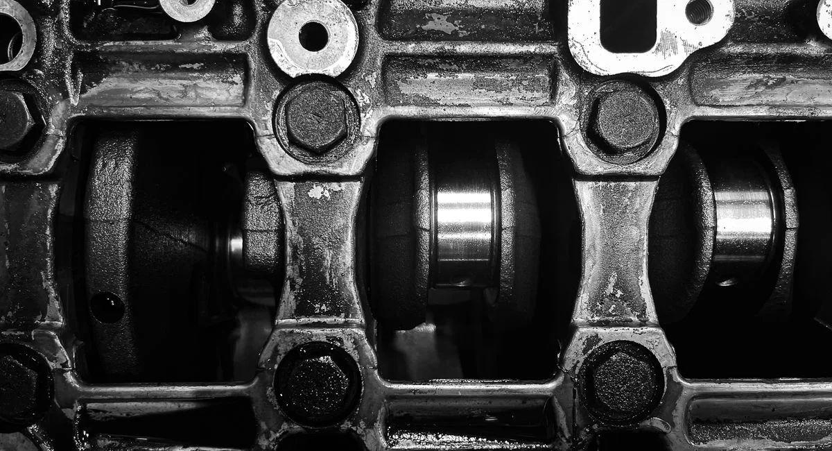 Detailed black and white close-up of a metal engine crankshaft mechanism.
