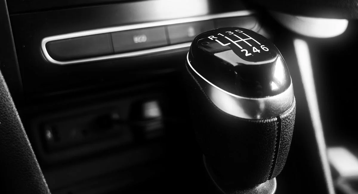 Black and white close-up of a manual gear shift in a modern car interior, highlighting sleek design.