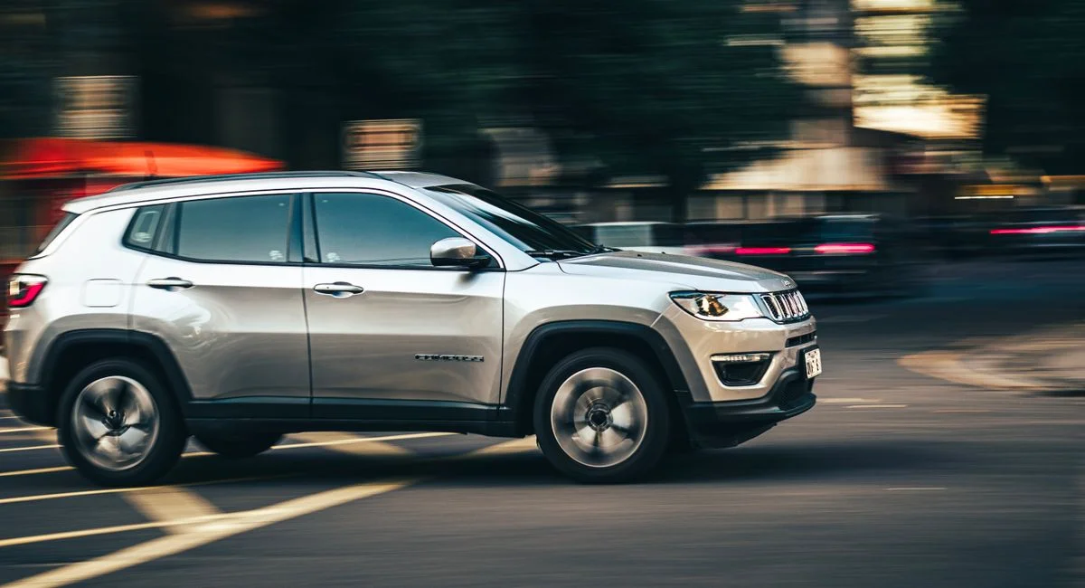 Dynamic side view of a silver SUV speeding downtown, capturing urban motion.