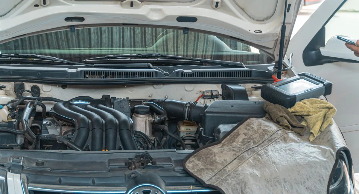 Close-up of a Volkswagen car engine undergoing repair in a garage, tools and diagnostic equipment in use.