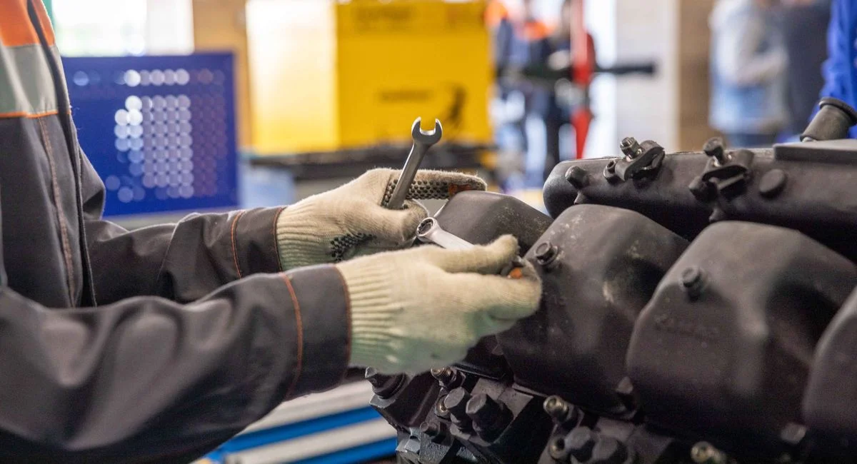 Close-up of a mechanic's hands working on an engine in a modern workshop.