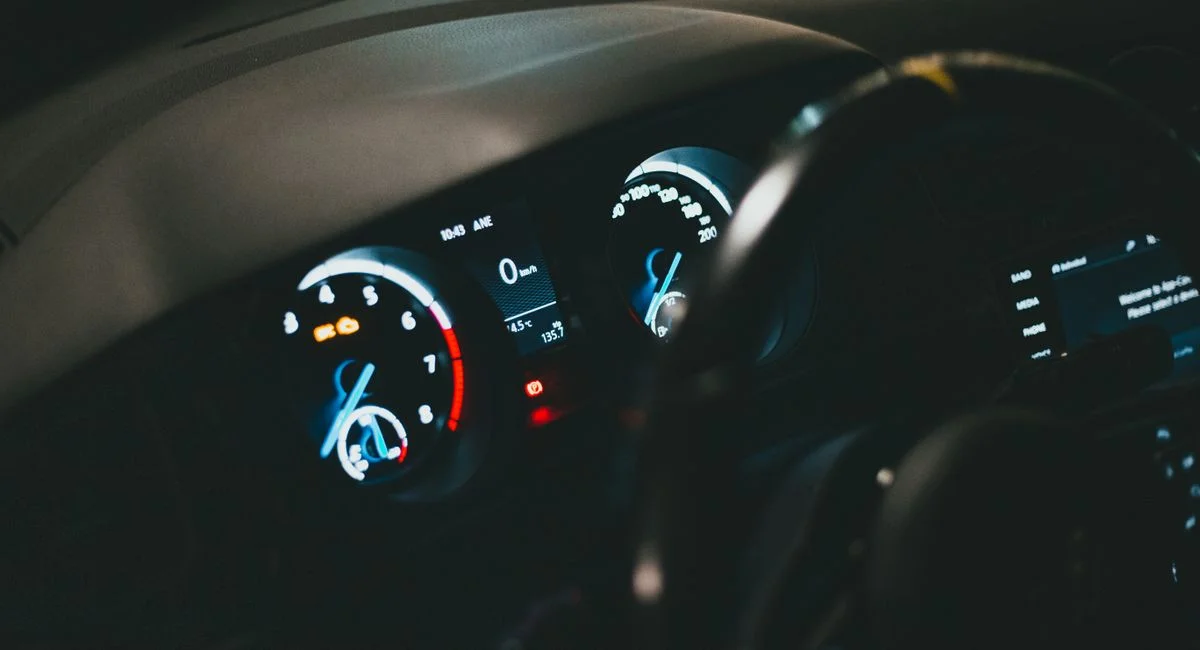 Detailed view of an illuminated car dashboard with speedometer and odometer visible.