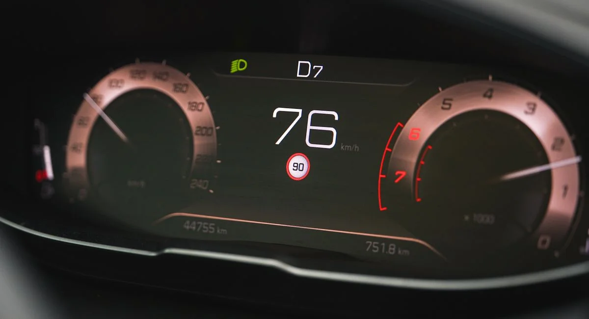 Close-up of a car speedometer display reading 76 km/h with a digital dashboard interface.