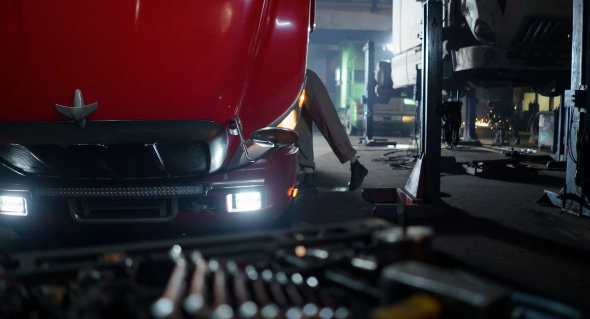 Mechanic working on a truck in a dimly lit garage, focused on repair and maintenance.