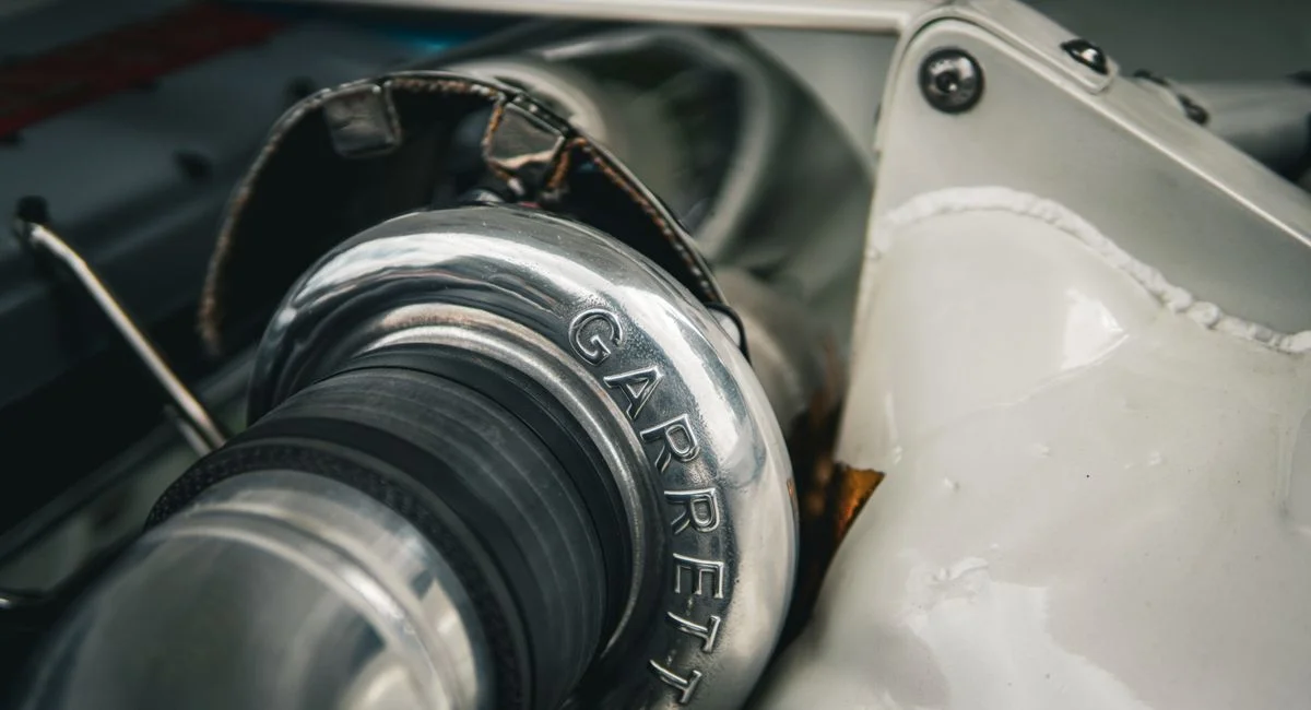 Detailed macro shot of a silver Garrett turbocharger part in an automotive setting.