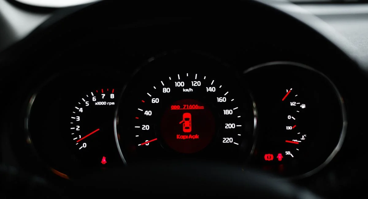 Car dashboard showing a warning light with various dials and gauges in focus.