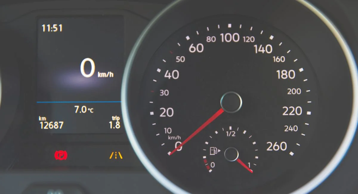 Detailed view of a car speedometer showing 0 km/h and fuel gauge with digital display.
